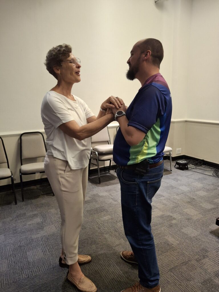 Duas pessoas frente a frente, com as mãos unidas, em uma atividade da primeira edição do Encontro Brasileiro de Reikianos, em 2025.