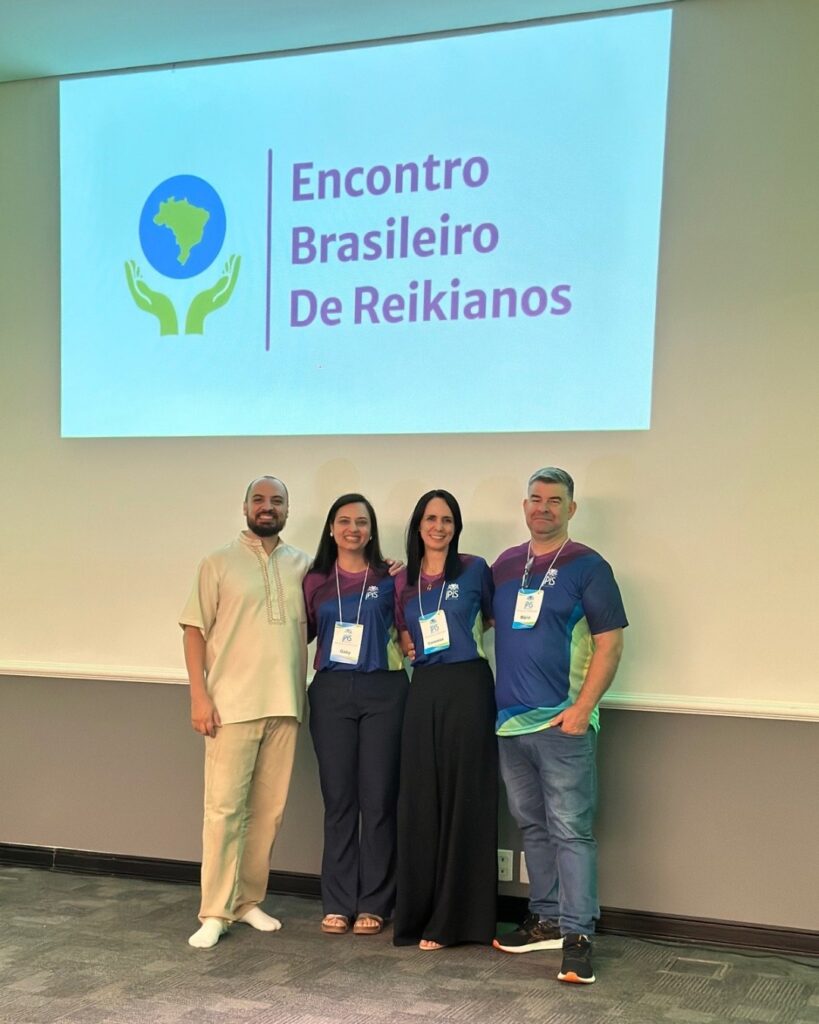 Pessoas reunidas diante da projeção da marca do Encontro Brasileiro de Reikianos, na segunda edição, em 2026.