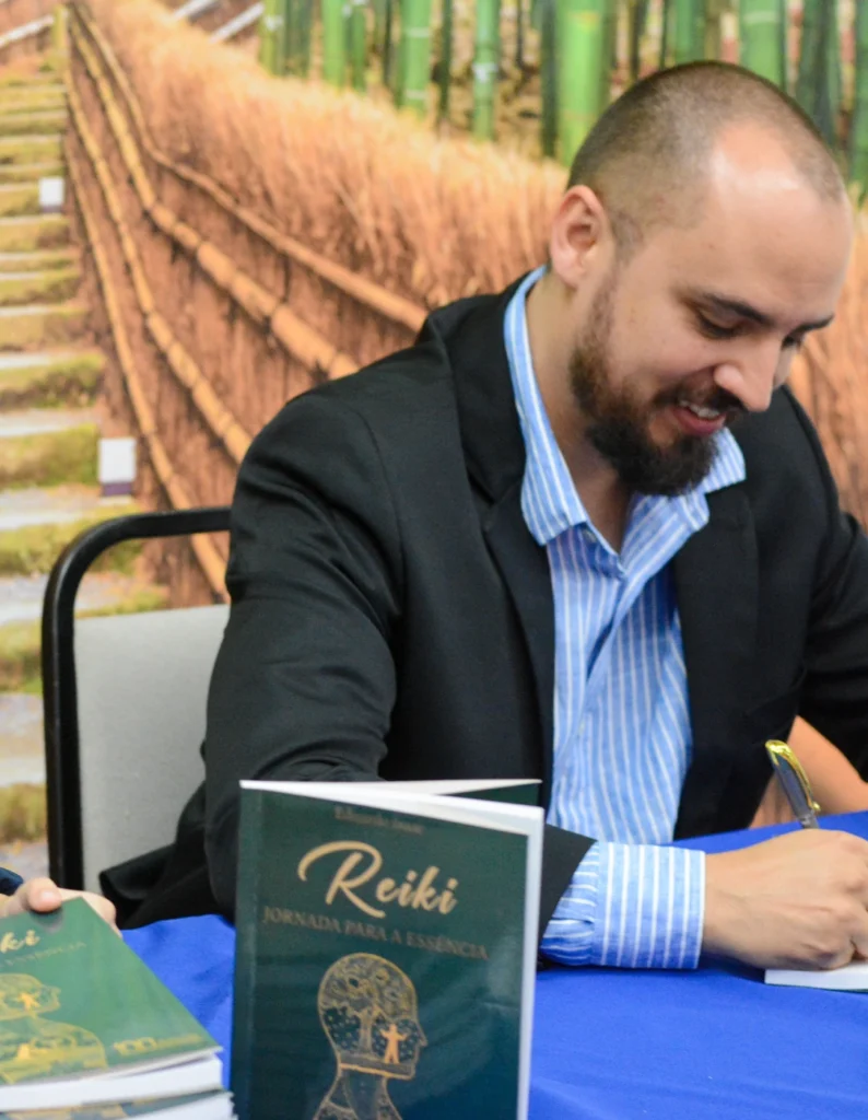 Registro do lançamento de Reiki: Jornada para a Essência, em 2022: momento de autógrafos, com exemplares da capa verde sobre a mesa.