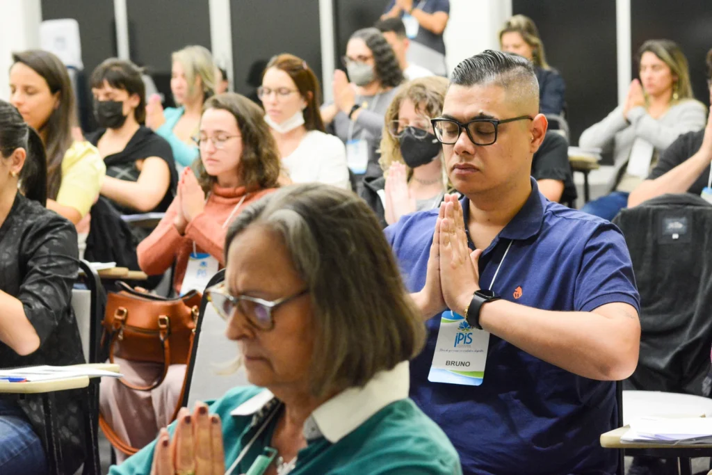 Participantes com as mãos unidas durante uma prática coletiva no evento de lançamento do livro e celebração dos 100 anos do Reiki, em 2022.